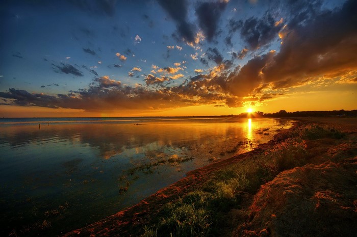 Sunset over a calm body of water with clouds