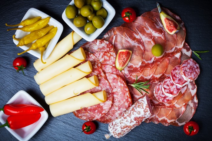 Charcuterie board with meats, cheese, olives, and peppers