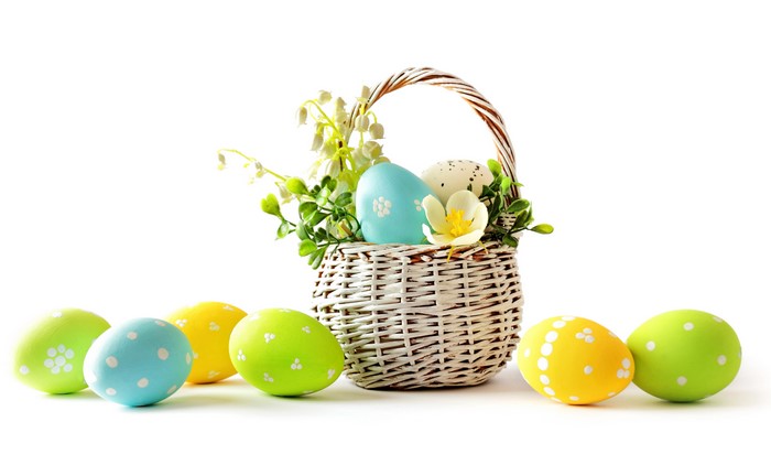 Easter eggs in a wicker basket with lilies of the valley