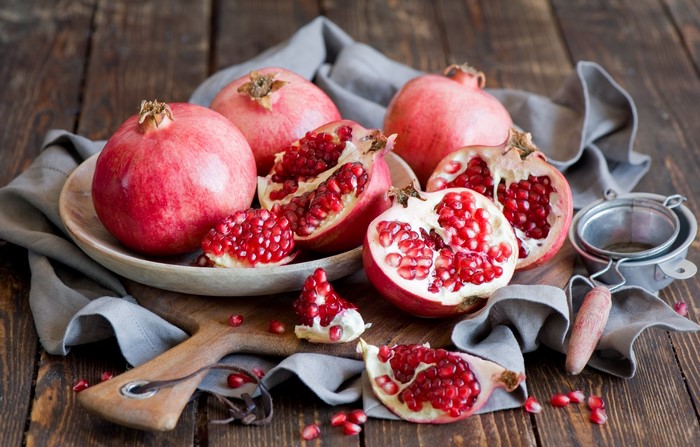Pomegranates on a wooden table with a grey cloth