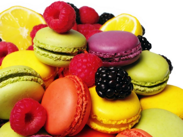 Assortment of colorful macarons with berries and lemon slices