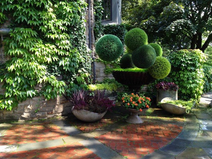 Topiary garden with ivy-covered stone wall and brick patio