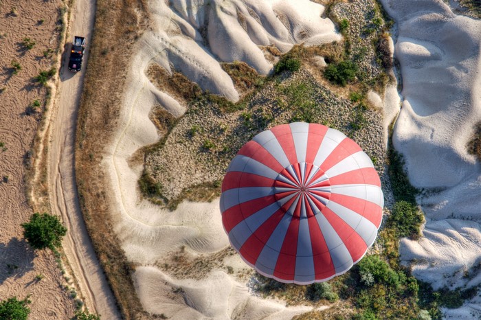 Hot air balloon over Cappadocia landscape with vehicle