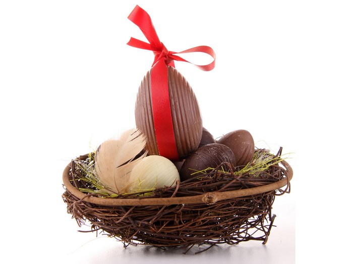 Chocolate Easter eggs in a nest with feathers and a red bow