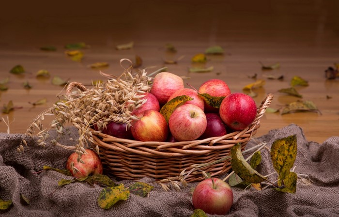 Basket of apples with wheat and autumn leaves