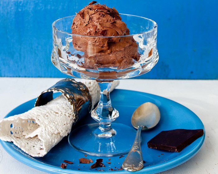 Chocolate ice cream in a glass bowl with a spoon and chocolate bar
