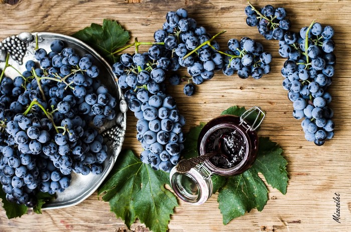 Grapes and grape jam on a wooden table