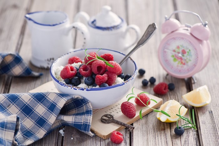 Still life with cottage cheese, berries, and alarm clock