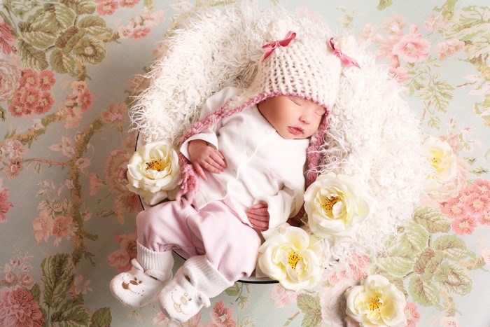 Newborn baby sleeping in a basket with roses