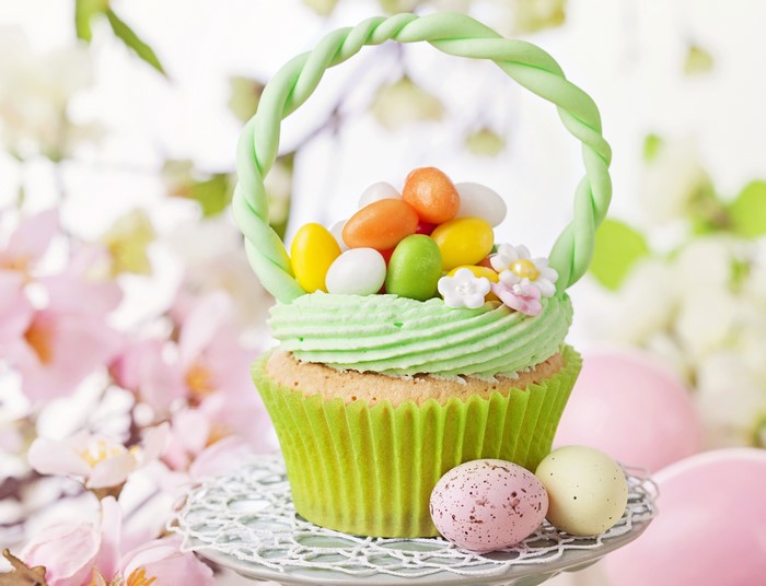 Easter cupcake with candy eggs and spring flowers