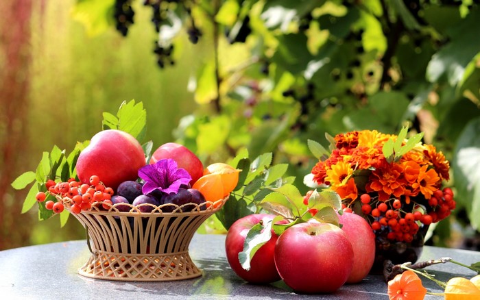 Still-life of apples, plums, and flowers in a basket