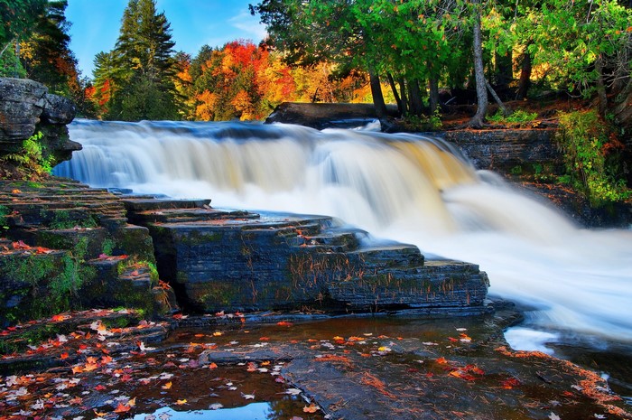 Waterfall cascading over layered stones in autumn forest