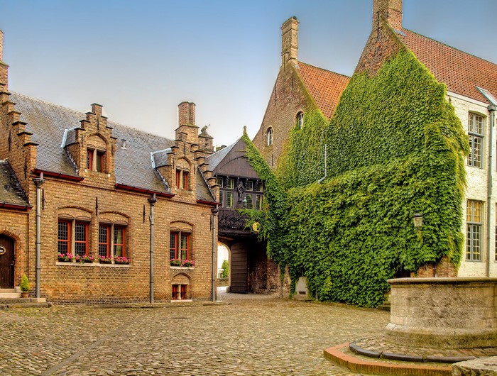 Brick houses with ivy and cobblestone courtyard in Bruges