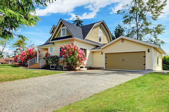 Yellow house with garage and pink flowers
