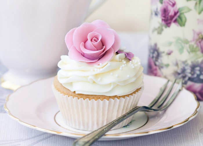 Cupcake with pink rose decoration on a plate