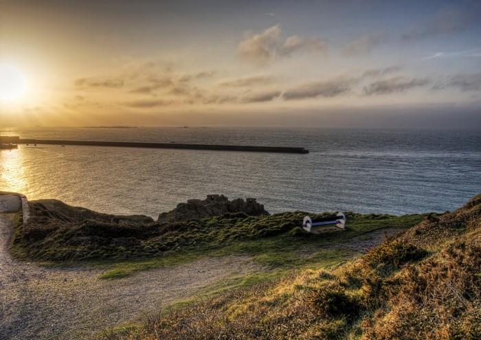 Alderney coast with a breakwater at sunset