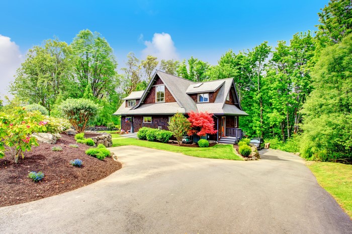 A large wooden house with a driveway and trees