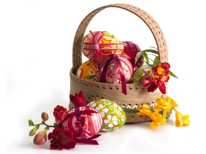 Easter eggs in a wicker basket with freesia flowers
