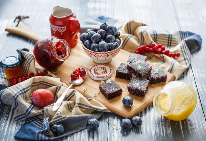 Plums, Jam, Honey, and Pastries on a Wooden Board