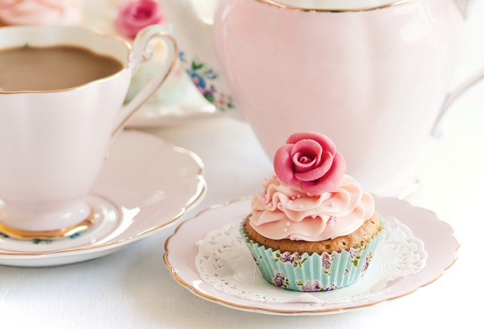 Tea cup and saucer with cupcake and teapot
