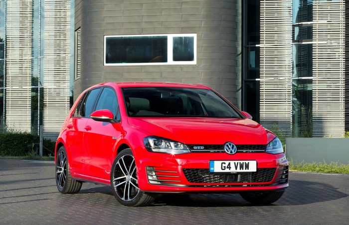 Red Volkswagen Golf VII GTD parked in front of a modern building