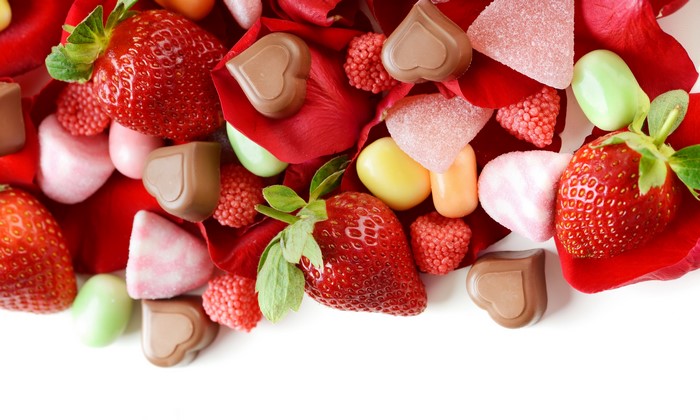 Strawberries and assorted candies on rose petals
