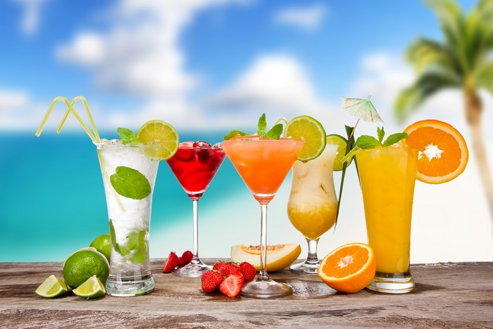 Assortment of colorful tropical cocktails with fruits on a wooden table