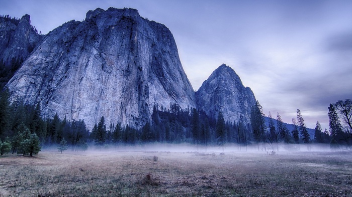 Misty meadow in front of large granite mountains
