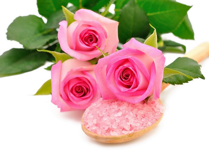 Three pink roses with bath salts on a wooden spoon