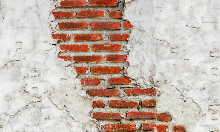 Cracked Plaster Wall Revealing Red Bricks Texture