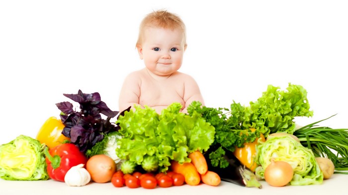 Baby with a pile of fresh vegetables