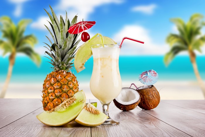 Pineapple, Melon, Coconut Drink on Beach Background