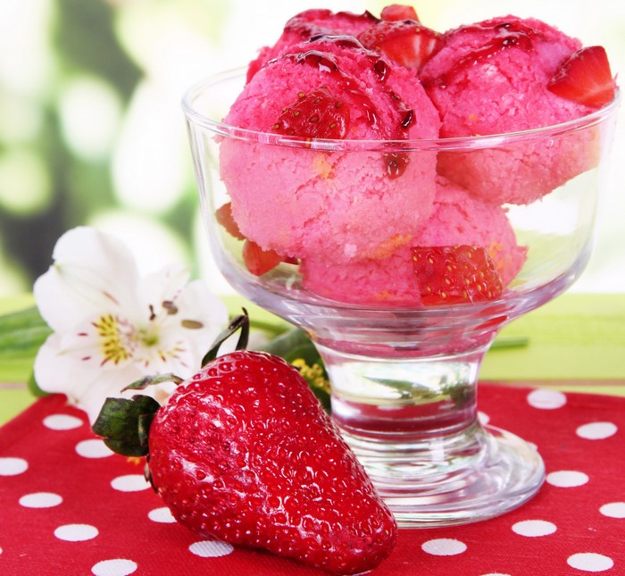 Strawberry ice cream in a glass bowl with fresh strawberry and flower