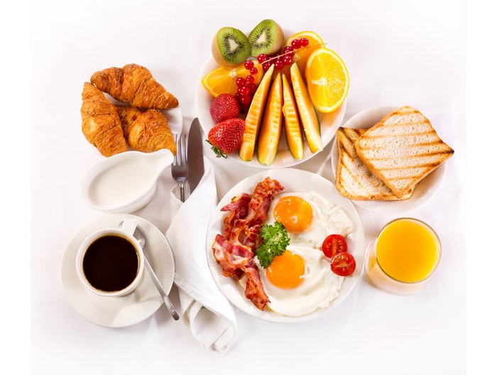 Breakfast with coffee, eggs, bacon, croissants, fruit, and toast