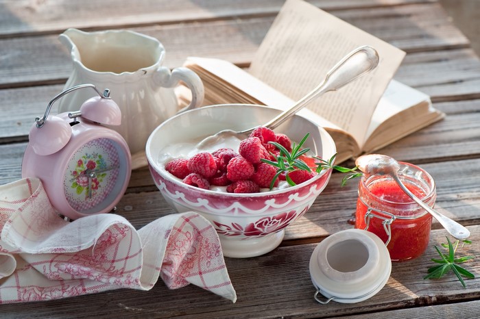 Still life with yogurt, raspberries, jam, and alarm clock
