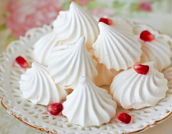 White meringues with pomegranate seeds on a decorative plate