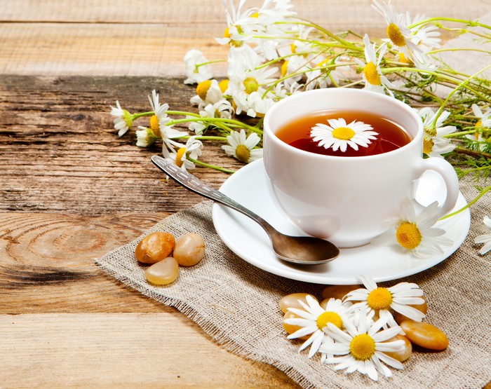 Cup of chamomile tea with flowers and stones