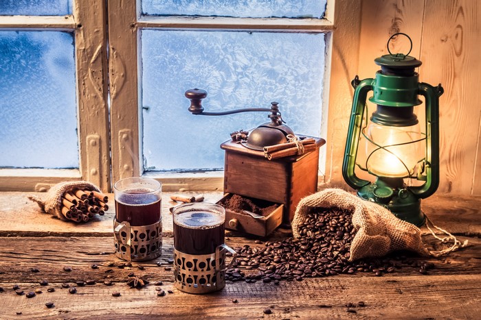 Coffee beans, grinder, and lantern by a frosty window