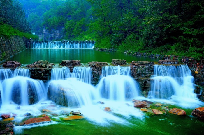Waterfalls cascading over rocks in a lush green forest