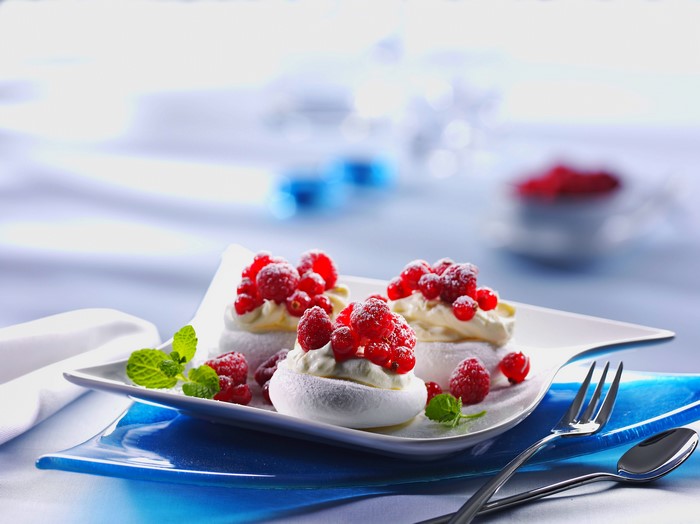 Meringue desserts with raspberries and currants on a plate