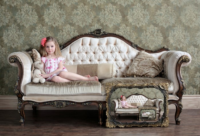 Girl with toy on ornate sofa