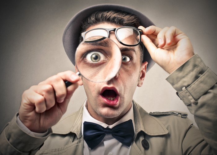 Man in Hat and Trench Coat with Magnifying Glass