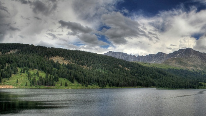 Lake and Forested Mountains Under Cloudy Sky