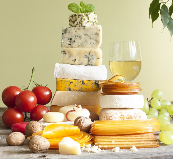 Cheese platter with tomatoes, nuts, grapes, and white wine