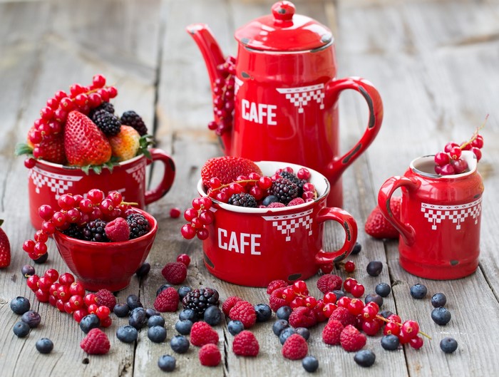 Red berries and fruits in red cups and teapot