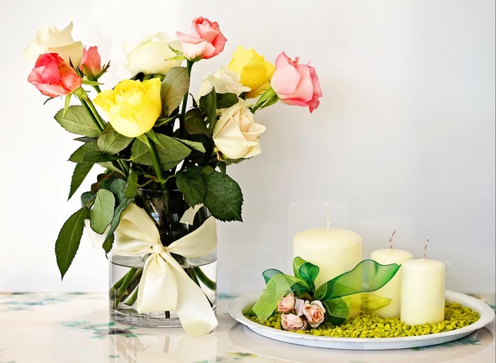 Roses in a vase with a bow and candles
