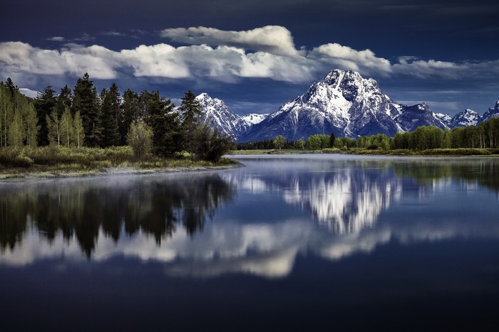 Grand Teton Mountains reflected in a lake with forest