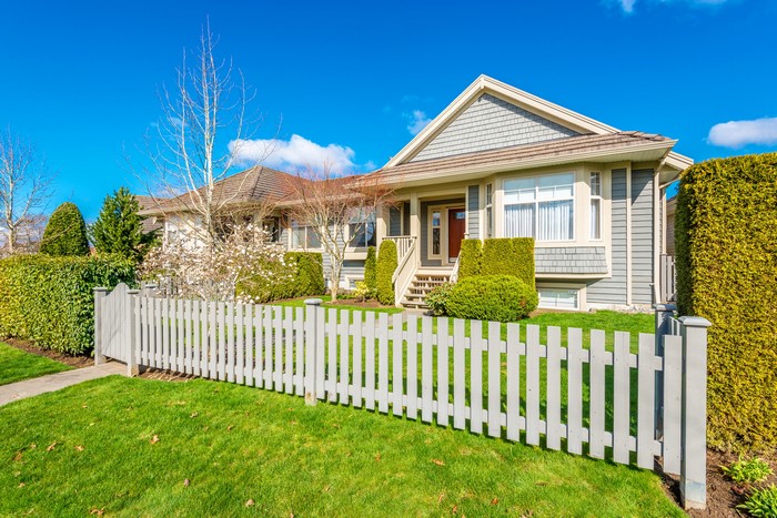 House with white picket fence and green lawn