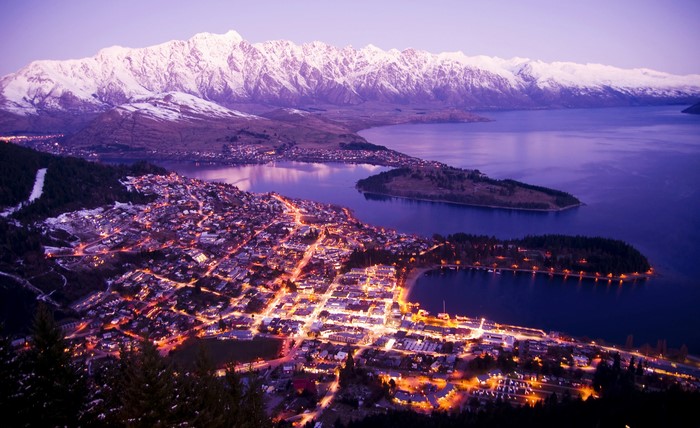 Queenstown at night with snow-capped mountains and lake