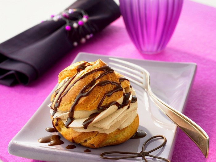 Cream puff drizzled with chocolate sauce on a plate